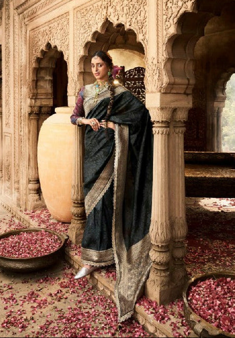 A fashion collage showing a woman wearing a dark navy or black saree with a metallic gold border and a purple blouse, posed in front of ornate arches and stone pillars. The collage includes multiple views of the same outfit in a decorative architectural setting with flower petals on the floor.