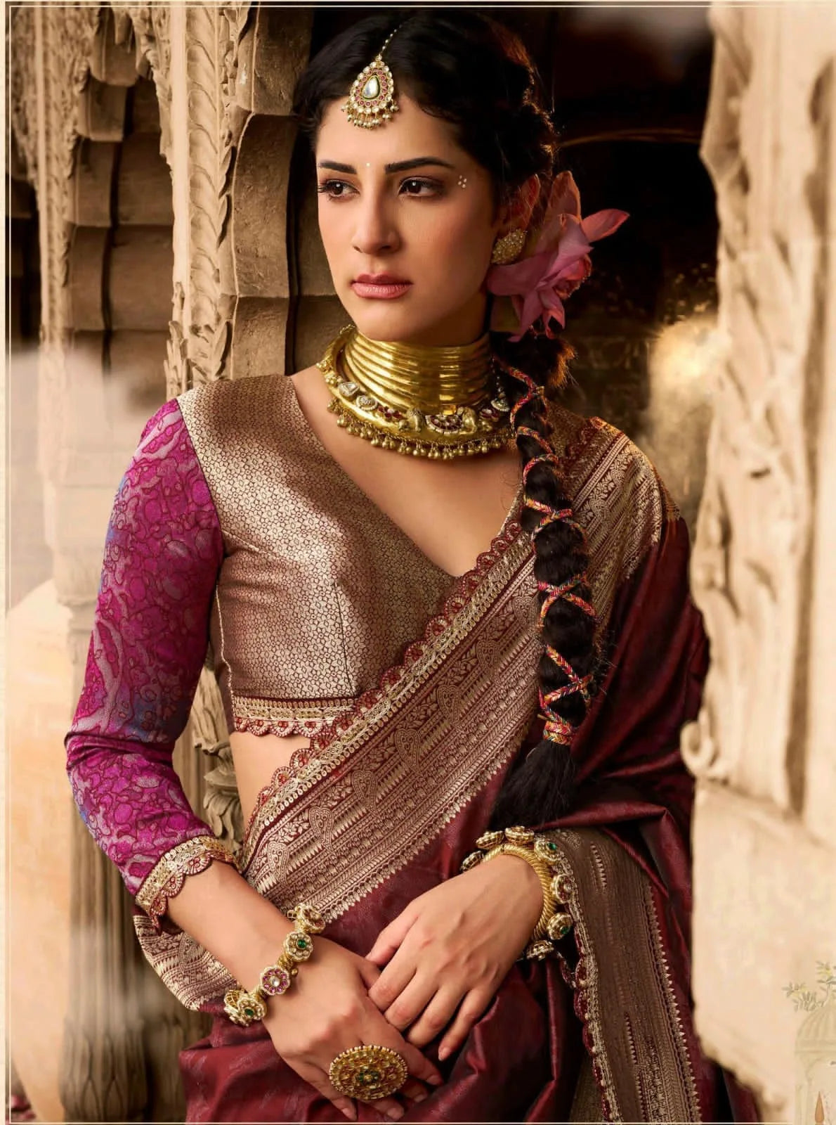 Woman in traditional attire with jewelry against a stone wall background